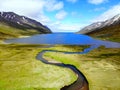 The aerial view of a blue creek flowing into the lake near Hedinsfjordur, Iceland