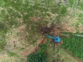 Aerial view on a blue excavator working in a blue field by a stone fence. Top down view.