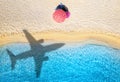 Aerial view of blue sea, airplane shadow, sandy beach, umbrella