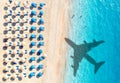 Aerial view of blue sea, airplane shadow, sandy beach, umbrellas
