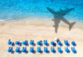 Aerial view of blue sea, airplane shadow, sandy beach, umbrellas