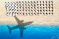 Aerial view of blue sea, airplane shadow, sandy beach, umbrellas