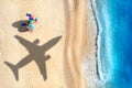 Aerial view of blue sea, airplane shadow, sandy beach, umbrellas