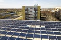 Aerial view of blue shiny solar photo voltaic panels system on commercial roof producing renewable clean energy on city landscape