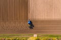 Aerial view of blue tractor plowing a field leaving tire tracks Royalty Free Stock Photo