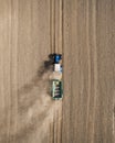 Aerial view of a blue tractor working in a field with a fertilizer and seed spreader