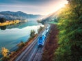 Aerial view of blue train near river in mountains at sunrise Royalty Free Stock Photo