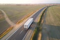 Aerial view of blurred fast moving semi-truck with cargo trailer driving on highway hauling goods in evening. Delivery