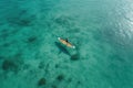 Aerial view of a boat on the turquoise sea. Aerial view of a woman on a surfboard in the turquoise waters of the Maldives, AI