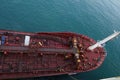 Aerial view on bow or forward part of red color bunker barge alongside of the cargo ship