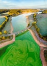 Aerial view of a bridge above the green lake surrounded by forest and agricultural fields at sunset Royalty Free Stock Photo