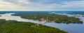 Aerial view on the bridge over the lake and trees in the forest on the shore. Blue lakes, islands and green forests from above on Royalty Free Stock Photo