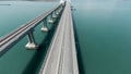 Aerial view of a bridge over the sea with calm water. Action. Long straight bridge with the moving vehicles above Royalty Free Stock Photo