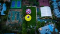 Aerial view of brightly-colored hot air balloons in a park preparing to take off