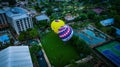 Aerial view of brightly-colored hot air balloons in a park preparing to take off