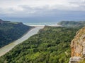 Aerial view of brown river surrounded by forest flowing into ocean at South Africa`s Wild Coast
