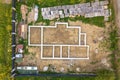 Aerial view of building site for future brick house, concrete foundation floor and stacks of yellow clay bricks for construction