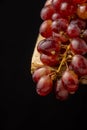 Aerial view of bunch of wet red grapes on rustic wooden table, black background, Royalty Free Stock Photo