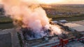 Aerial view of burnt industrial warehouse or logistics center building after big fire with huge smoke from burned roof Royalty Free Stock Photo