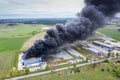 Aerial view of burnt industrial warehouse or logistics center building after big fire with huge smoke from burned roof