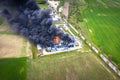 Aerial view of burnt industrial warehouse or logistics center building after big fire with huge smoke from burned roof