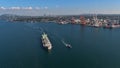 Aerial view of Burrard Inlet in Vancouver with bulk carrier passing by and container port with cranes.