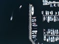 Aerial view of a bustling marina with a variety of different-sized boats docked in the water.