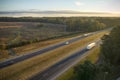 Aerial view of busy american highway with fast moving traffic surrounded by fall forest trees. Interstate transportation