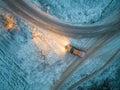 Aerial view of a car driving through a forest at dusk in winter time. Shot taken by a drone Royalty Free Stock Photo