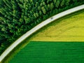 Aerial view of car driving on road along the green forest and potato with yellow rapeseed fields Royalty Free Stock Photo