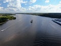 Aerial view cargo merchant ship sails along the river. Transport of goods by river barges. Beautiful landscape of the river.