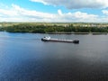 Aerial view cargo merchant ship sails along the river. Transport of goods by river barges. Beautiful landscape of the river.