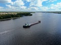 Aerial view cargo merchant ship sails along the river. Transport of goods by river barges. Beautiful landscape of the river.