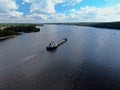 Aerial view cargo merchant ship sails along the river. Transport of goods by river barges. Beautiful landscape of the river