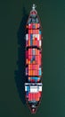 Aerial view of a cargo ship loaded with colorful containers, navigating through calm green waters Royalty Free Stock Photo