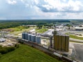 Aerial view of a cargo train by a farm with tall grain elevators and tanks in Delaware