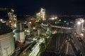 Aerial view of cement factory with high concrete plant structure and tower cranes at industrial production area at night