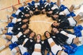 Aerial view of a cheerleading squad lying down in the circle and holding pom-poms in their hands.