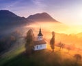 Aerial view of small church on the hill and low clouds at sunrise