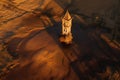 an aerial view of a church tower in the middle of a field at sunset or sunrise or sunset, with a shadow of a tree on the ground