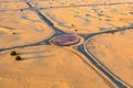 Aerial view of circle roundabout, half desert road or street with sand dune in Dubai City, United Arab Emirates or UAE. Natural