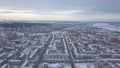 Aerial view of city buildings covered with snow, roads and large river on the background against grey evening sky in Royalty Free Stock Photo