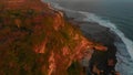 Aerial view of cliffy coastline with ocean at sunset tones in Uluwatu, Bali