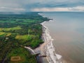 Aerial view of coastline with black sand beach, dirty ocean and waves in Balian, Bali Royalty Free Stock Photo