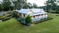 Aerial view of colonial sandstone cottage house with picket fence, garden, grass and eucalyptus gum trees