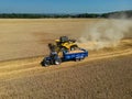 Aerial view of a combine harvester cutting the golden wheat while filling the trailer with grain in the English Countryside