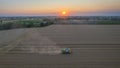 aerial view combine harvester cut thresh wheat grain in large field at early sunset in summer time Royalty Free Stock Photo