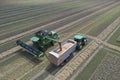 Aerial view of a combine harvester and tractor working in agriculture. Harvest grain field, summer season. Top view dron photo.