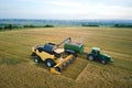 Aerial view of combine harvester unloading grain in cargo trailer working during harvesting season on large ripe wheat Royalty Free Stock Photo