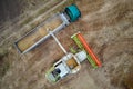 Aerial view of combine harvester unloading grain in cargo trailer working during harvesting season on large ripe wheat Royalty Free Stock Photo